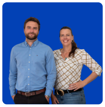 Twee mensen staan naast elkaar voor een effen blauwe achtergrond, beide lachen naar de camera.